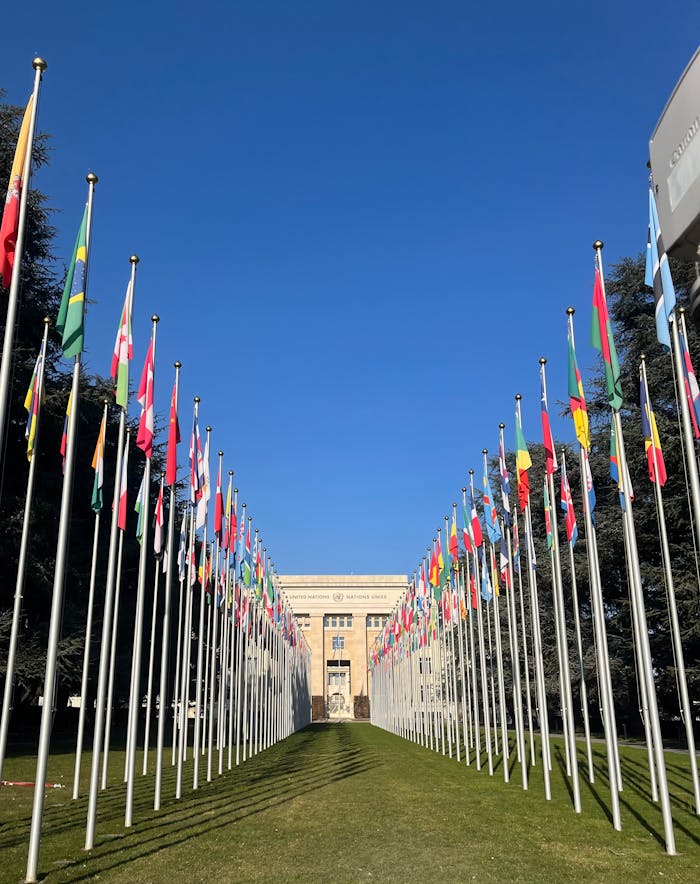 Flags outside the United Nations Office in Geneva under a clear blue sky.