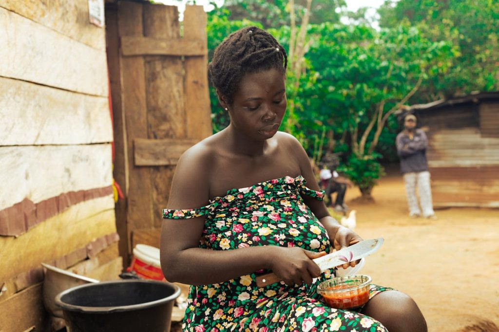 Woman in floral dress preparing vegetables, highlighting traditional lifestyle in a rural setting.